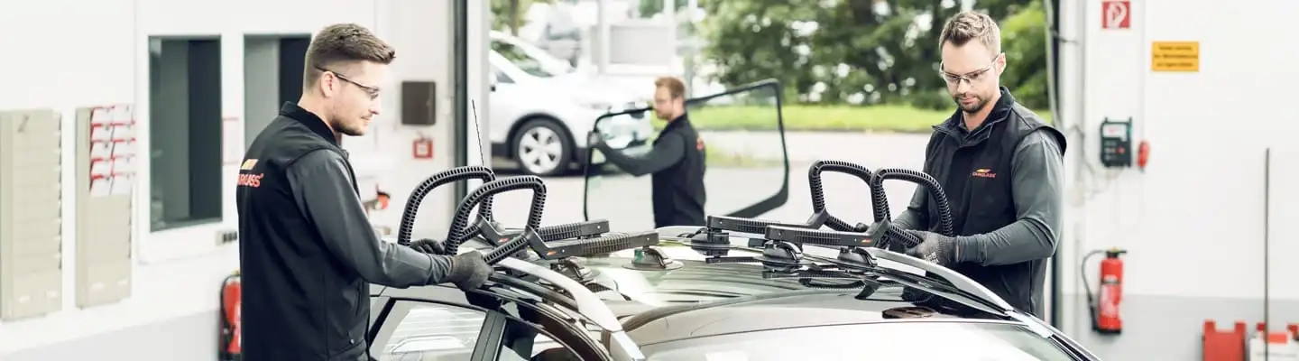 Zwei Monteure setzen ein Dachfenster in ein Auto ein