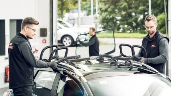 Zwei Monteure setzen ein Dachfenster in ein Auto ein