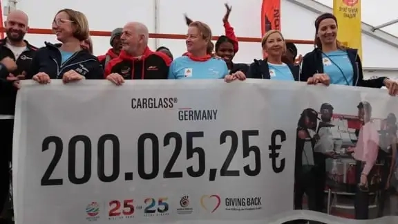Mehrere Menschen die einen großen Banner mit einer Summe von 200.025,26€ hochhalten.