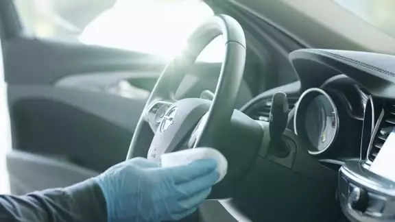 Ein Lenkrad wird von einem Carglass Mitarbeiter desinfiziert