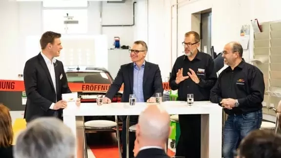 Vier Menschen hinter einem weißen Tisch, die sich vor einem Publikum austauschen