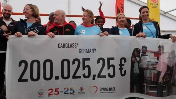 Mehrere Menschen die einen großen Banner mit einer Summe von 200.025,26€ hochhalten.