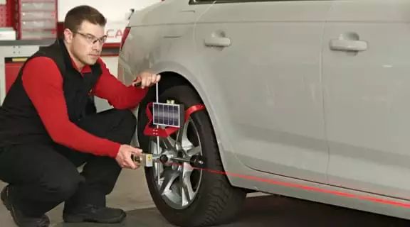 Monteur, der einen Laser am Reifen des Autos anbringt und ausrichtet