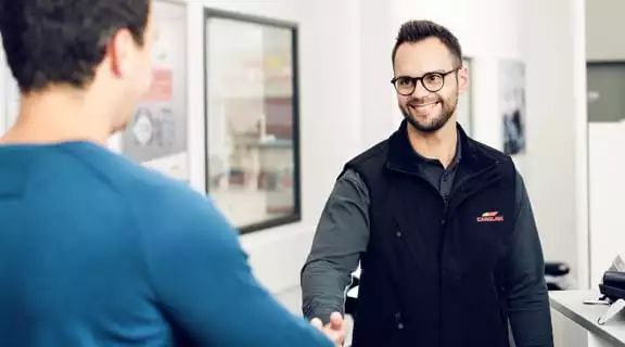 Kunde redet mit Mitarbeiter im Büro und reicht ihm die Hand