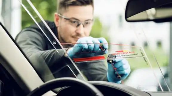 Monteur misst konzentriert eine Windschutzscheibe aus