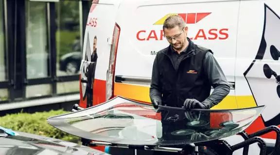 Monteur arbeitet im Freien, vor einem Transporter an einer Scheibe
