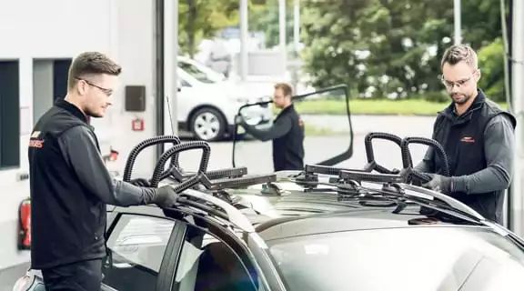 Zwei Monteure setzen ein Dachfenster in ein Auto ein