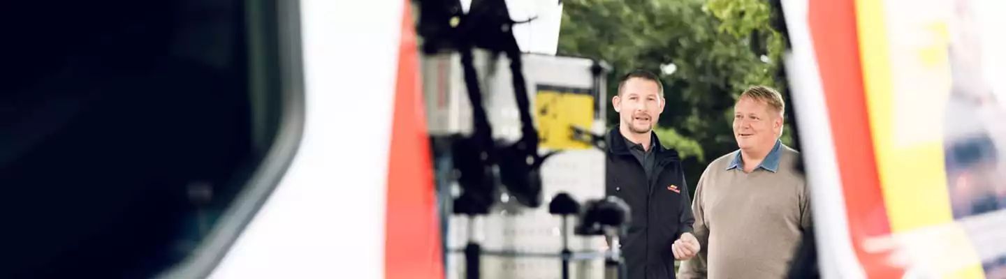 Kunde und Monteur gucken durch Tür eines Transporters
