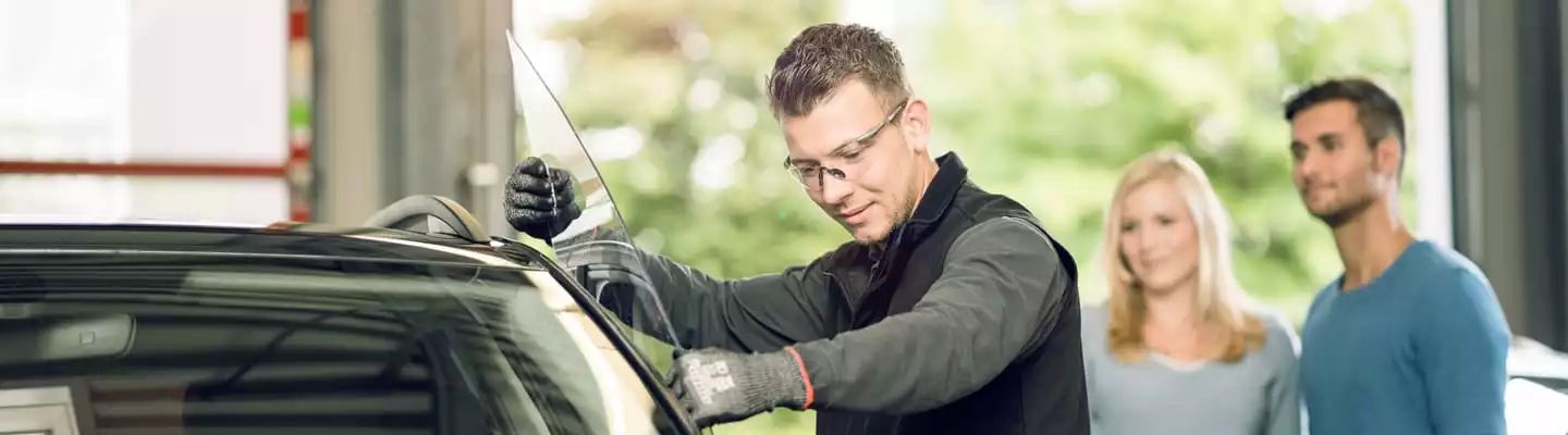 Zwei Kunden beobachten wie ein Monteur eine temporäre Scheibe einsetzt