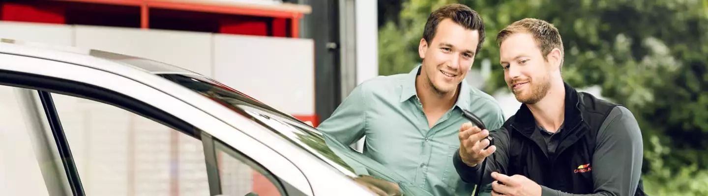 Kunde wird von Monteur vor einem Auto beraten