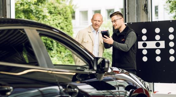 Monteur erklärt Kunde die Kalibrierung eines Fahrzeugs